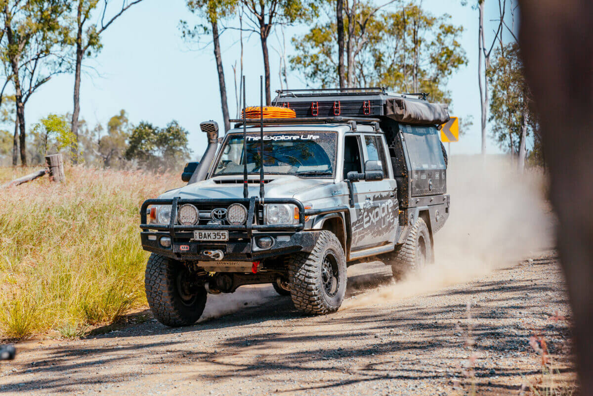 A Toyota 79 series with lots of equipment is driving down a dusty track.