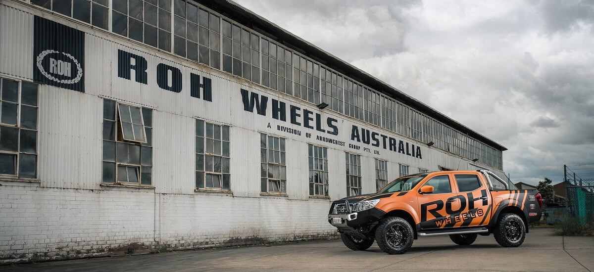 A Toyota with orange and black ROH Wheels branding sits outside the ROH Wheels factory.