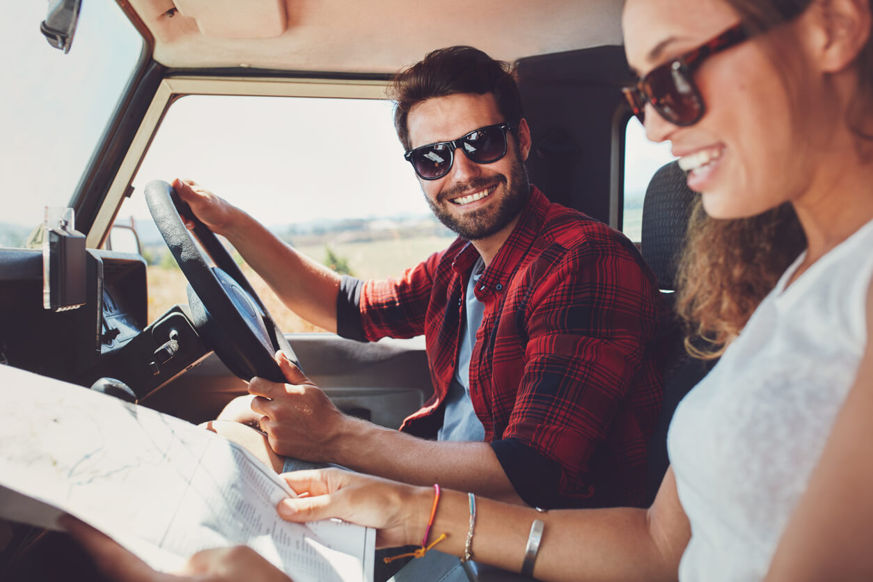 Man and woman in the car while passenger looks at a roadmap