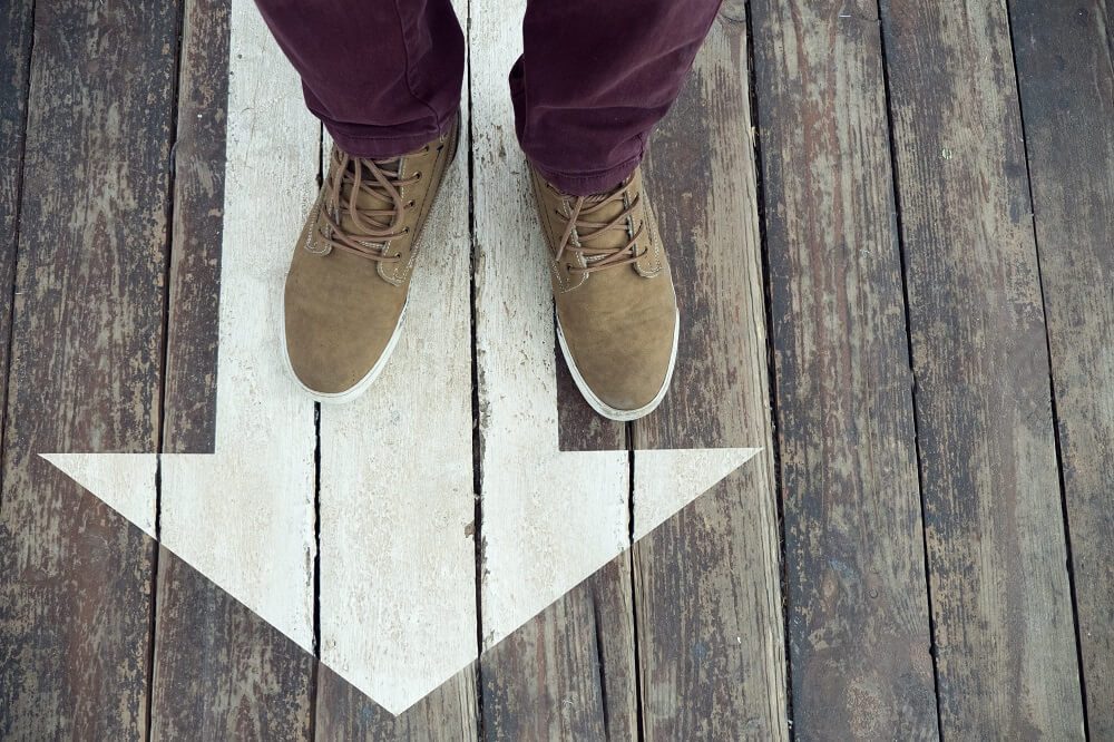 Person standing on arrow pointing in a direction