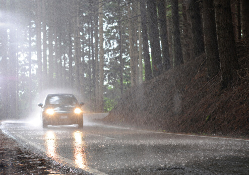 A car travels on a wet road being cautious of over and understeer.