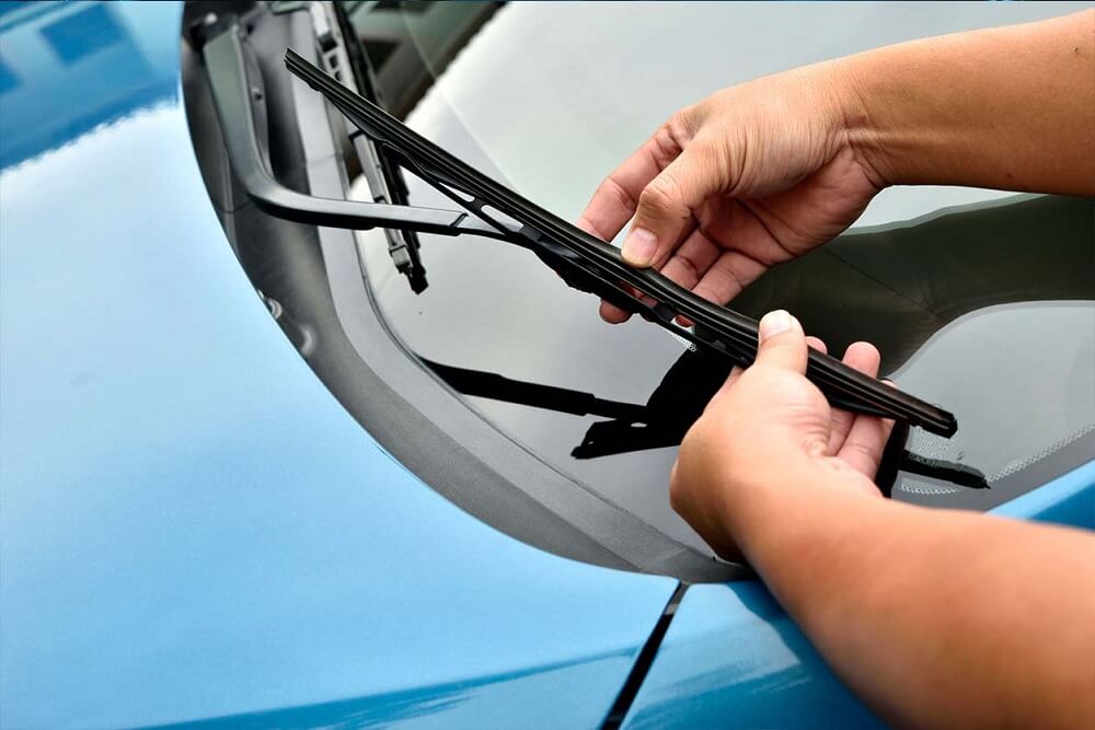A person inspects the condition of their wiper blades before driving off.
