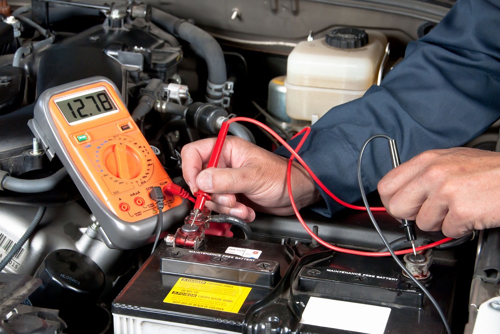 Service mechanic testing a car battery