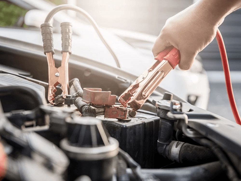 Jumper cables are being placed onto a car battery for testing.