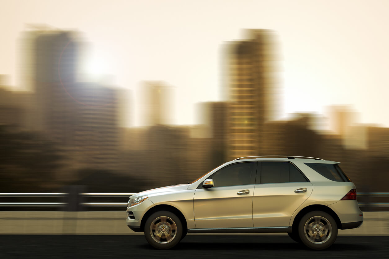 An SUV drives through the city on a bridge.