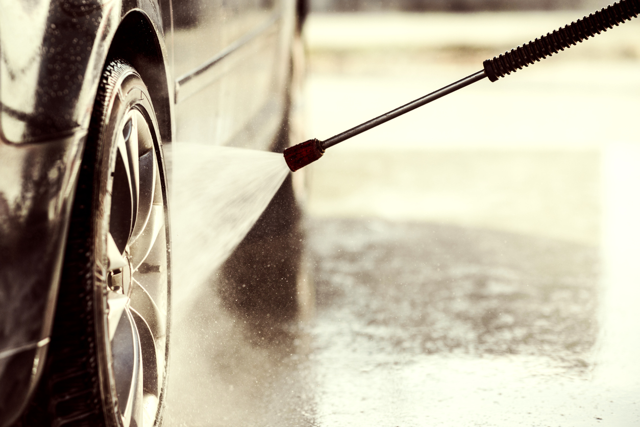 Washing tyres with pressurised water from a sprayer to loosen dirt.