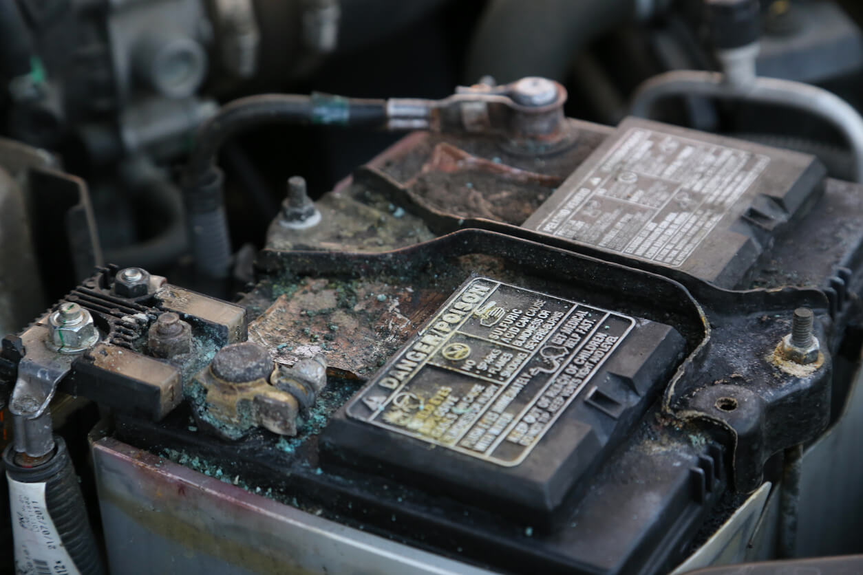 A dirty and heavily corroded automotive battery.